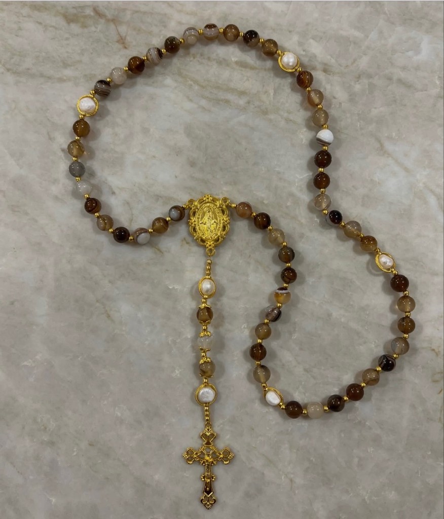 Brown and honey agate rosary with pearl Our Father beads, a gold Miraculous Medal, and an ornate gold cross.